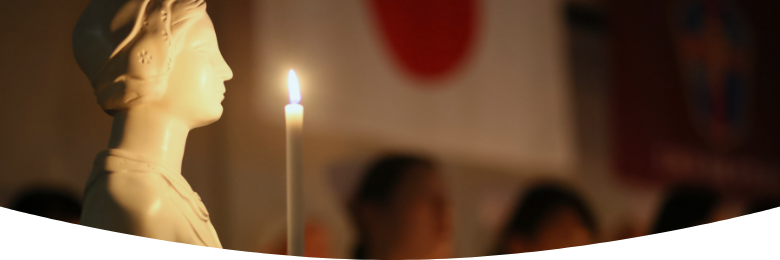 授業の様子 マネキンがベッドに寝ていて、先生が立ち学生たちが椅子に座って話を聞いている